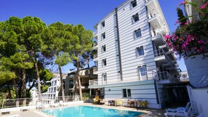 Un hôtel doté d’une piscine, d’un espace extérieur aménagé et d’un bâtiment à plusieurs étages avec des balcons.