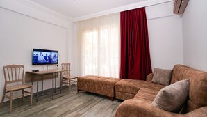 Un salon avec un canapé, un téléviseur, une table et des chaises.