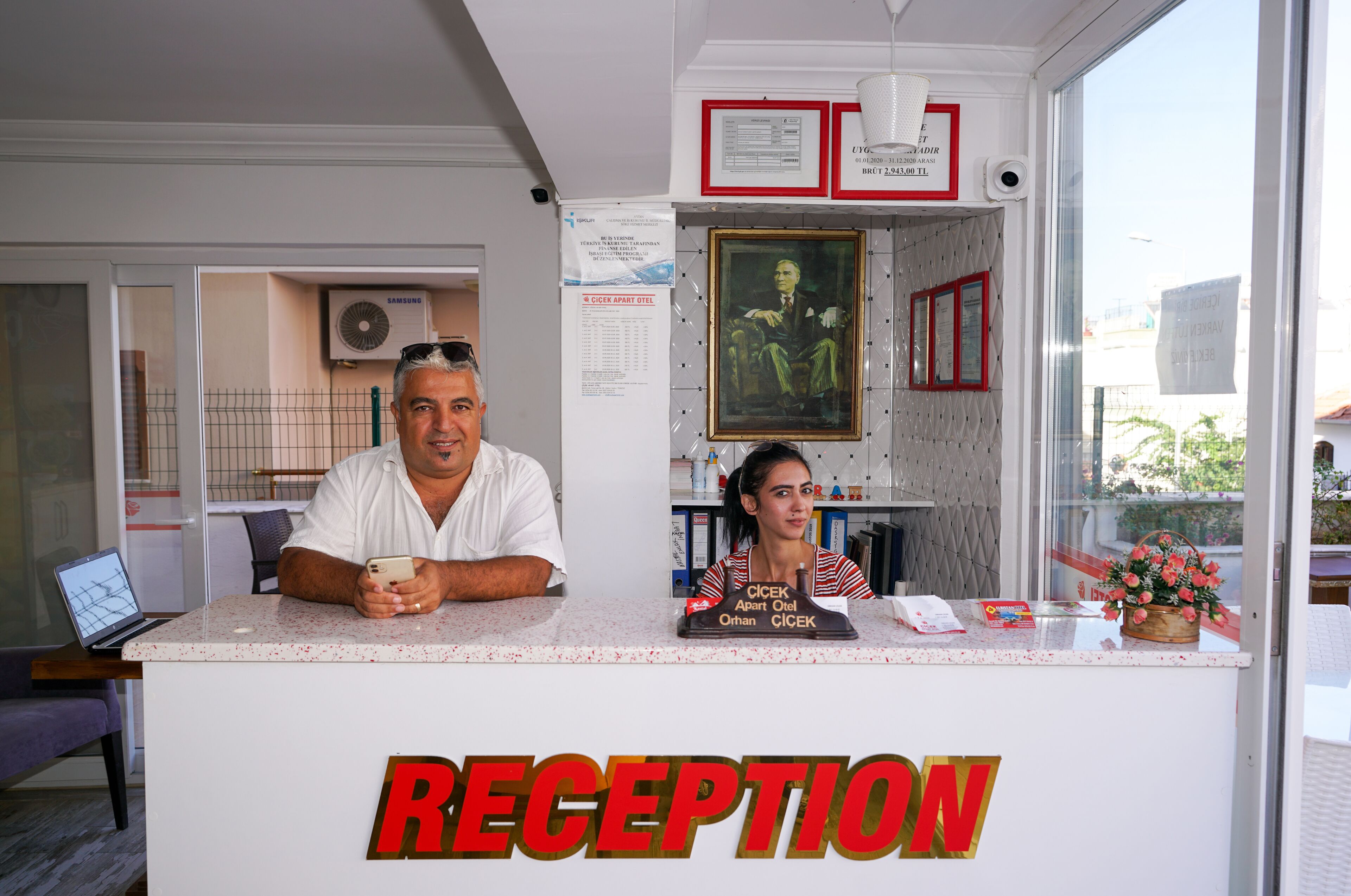 A reception desk with a sign reading "RECEPTION" and a framed portrait above it.
