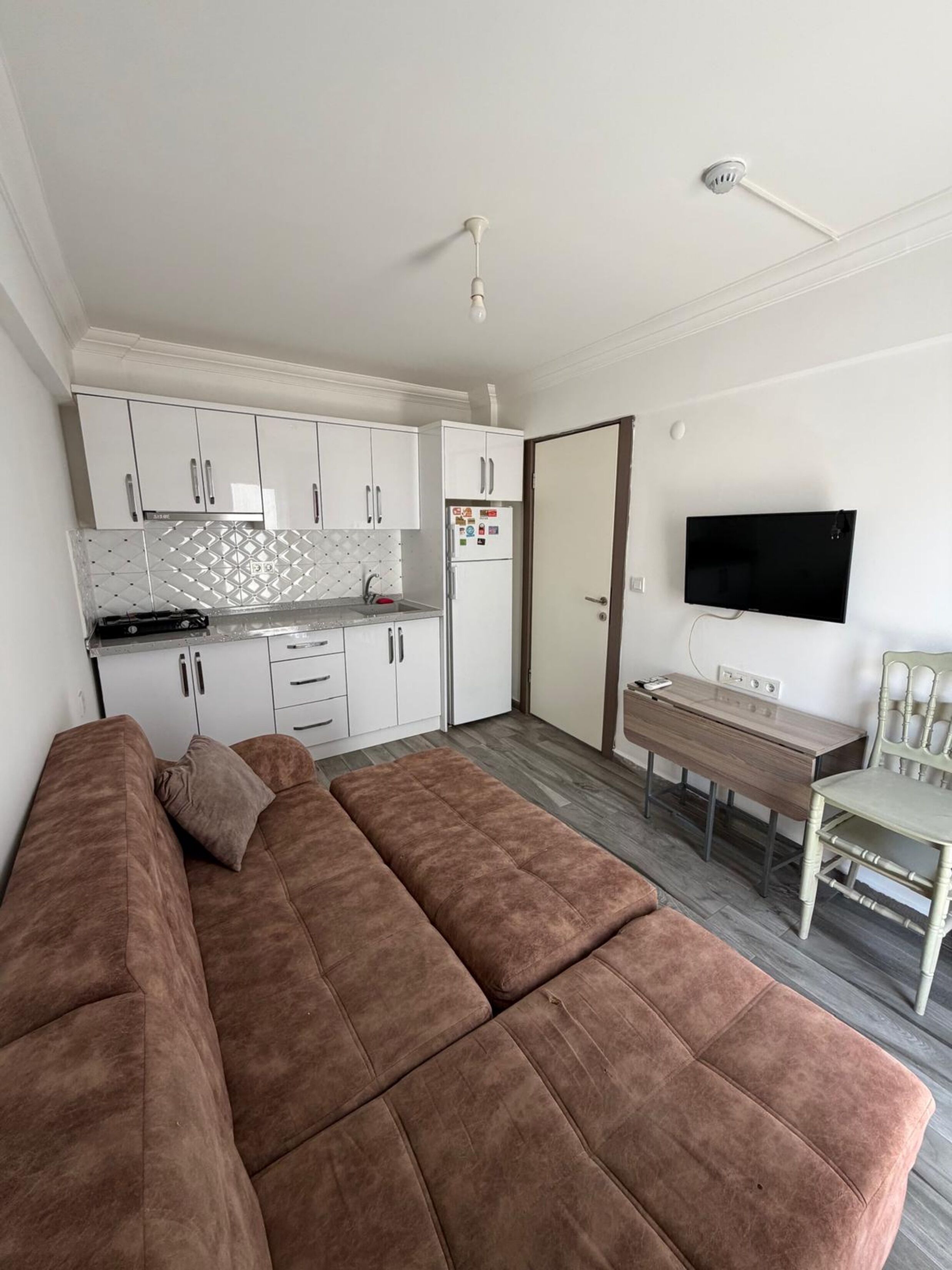 A compact living space with a kitchenette, a sofa, a TV, and a dining area.