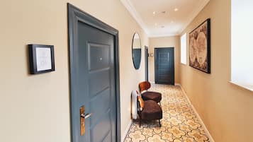 A hallway with a blue door, a framed picture, a mirror, and a patterned floor.