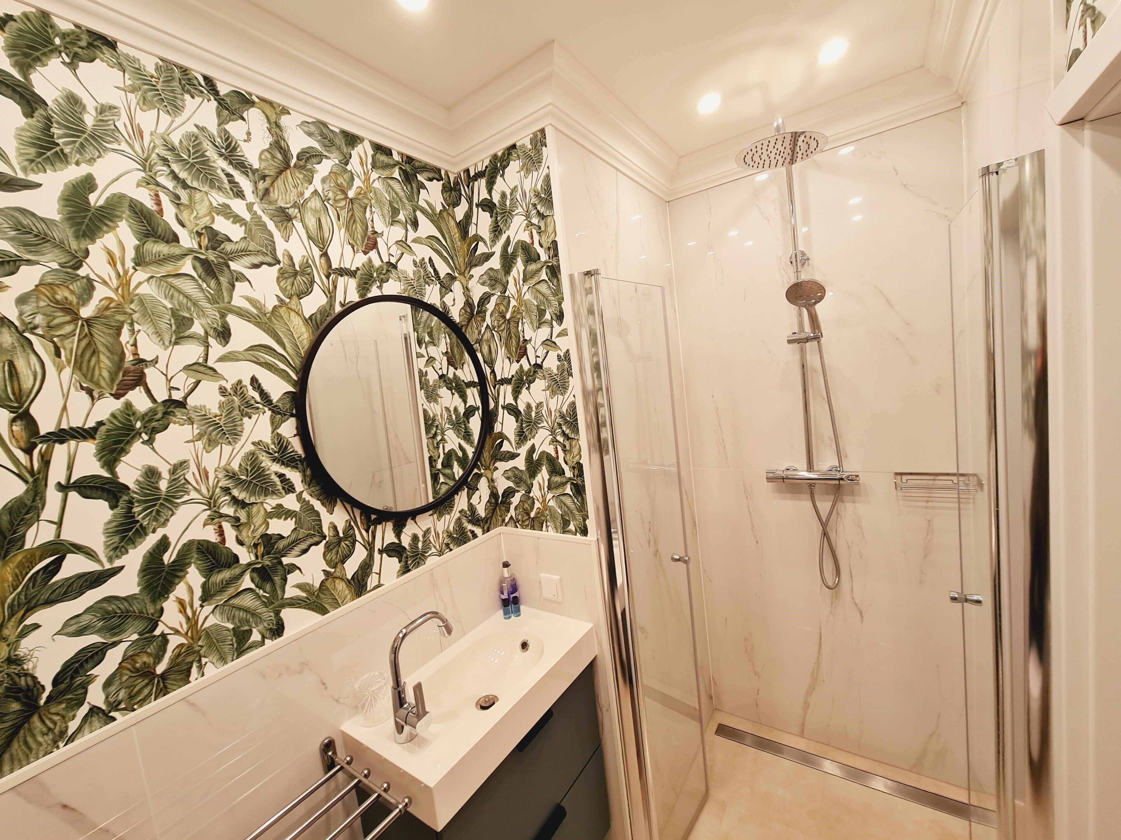 Une salle de bain avec une douche, un lavabo et un miroir.
