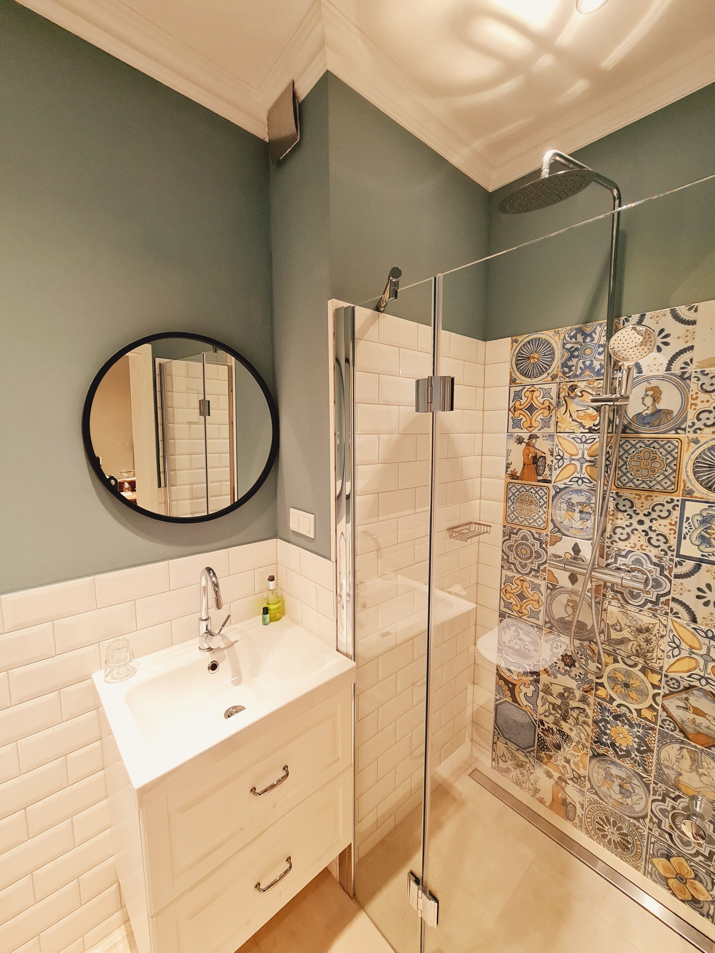 A bathroom with a white sink, a mirror, and a shower with a glass door.
