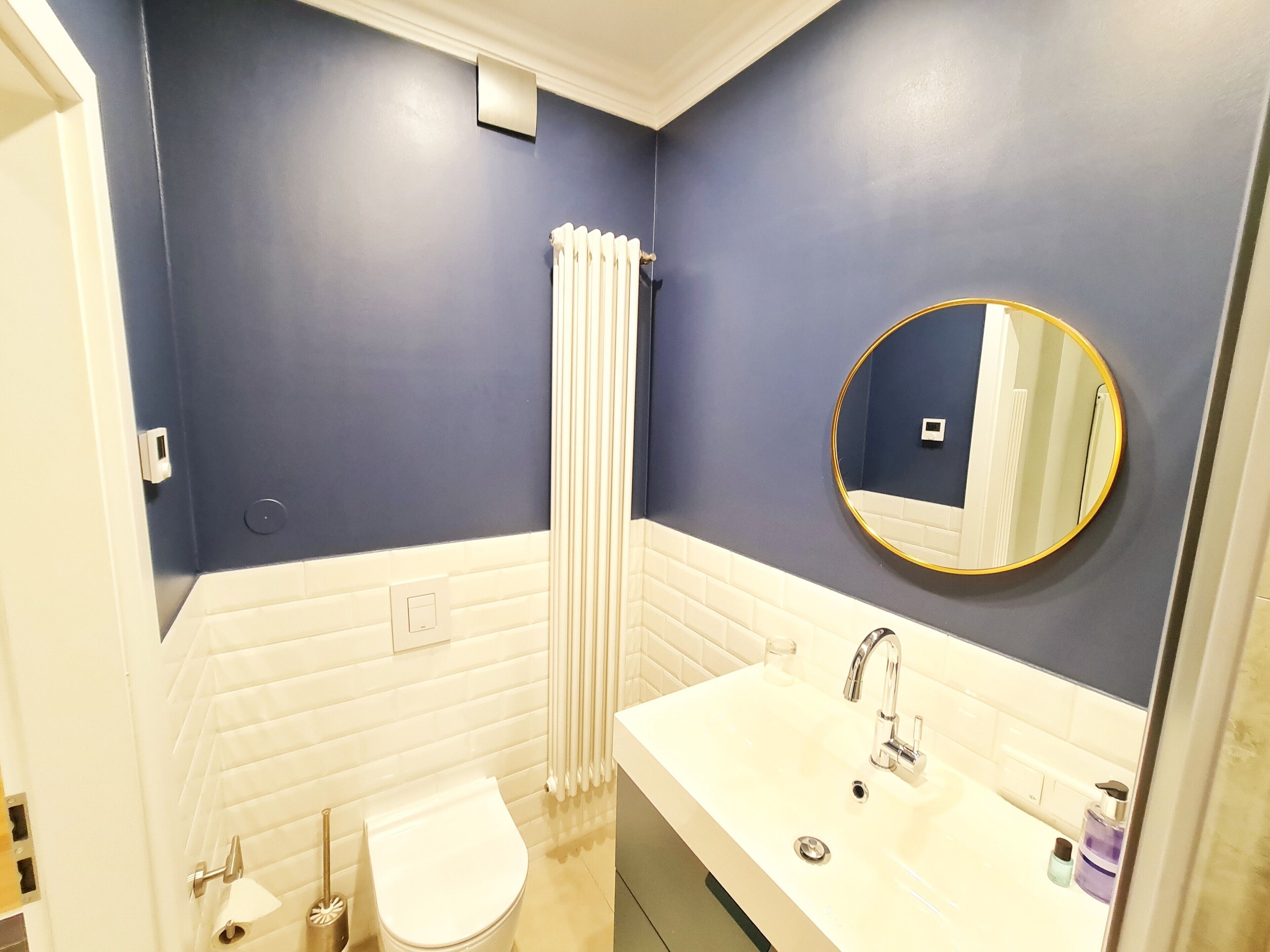A bathroom with a white sink, a round mirror, a toilet, and a shower curtain.