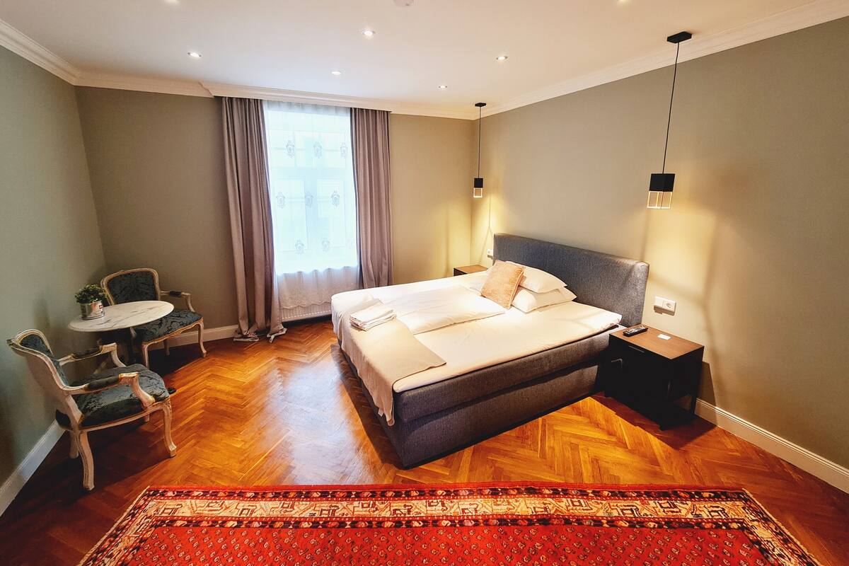 A modern hotel room with a large bed, a small table, and a chair.