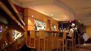 A bar area with a piano, wooden furniture, and hanging lights. - Radisson Blu Erfurt (Erfurt)