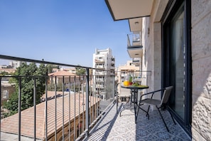 A balcony with a table, chairs, and a view of the cityscape. - Eshel Suites (Jerusalem)