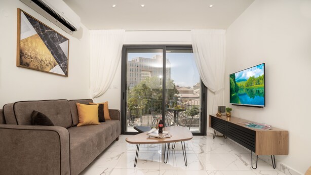 Uma sala de estar moderna com sofá, mesa de centro e televisão.