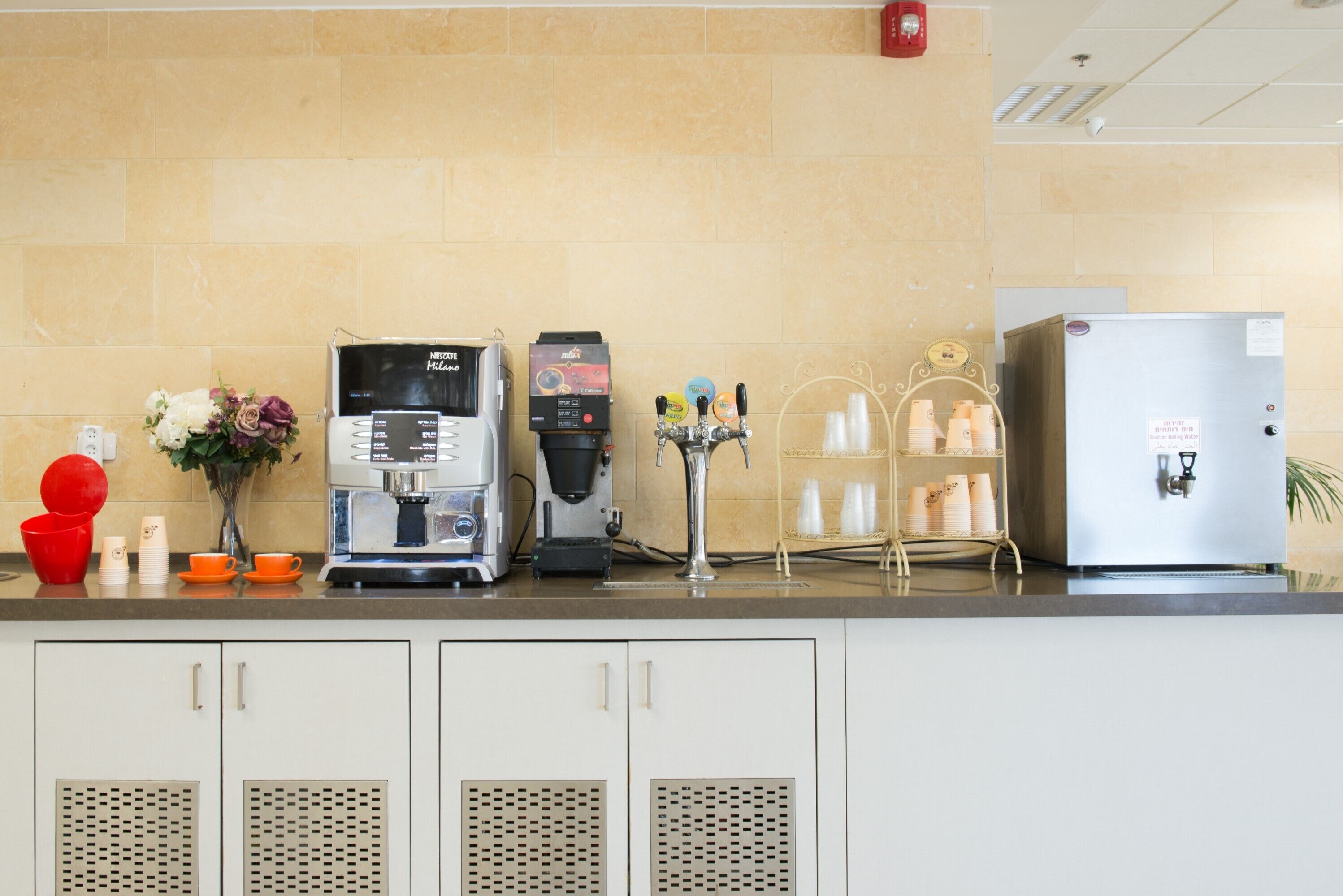 Una cocina equipada con cafetera, refrigerador y dispensador de bebidas.