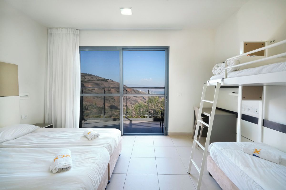 A hotel room with two beds, a balcony, and a view of the hills.