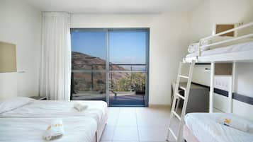 A hotel room with two beds, a balcony, and a view of the hills.