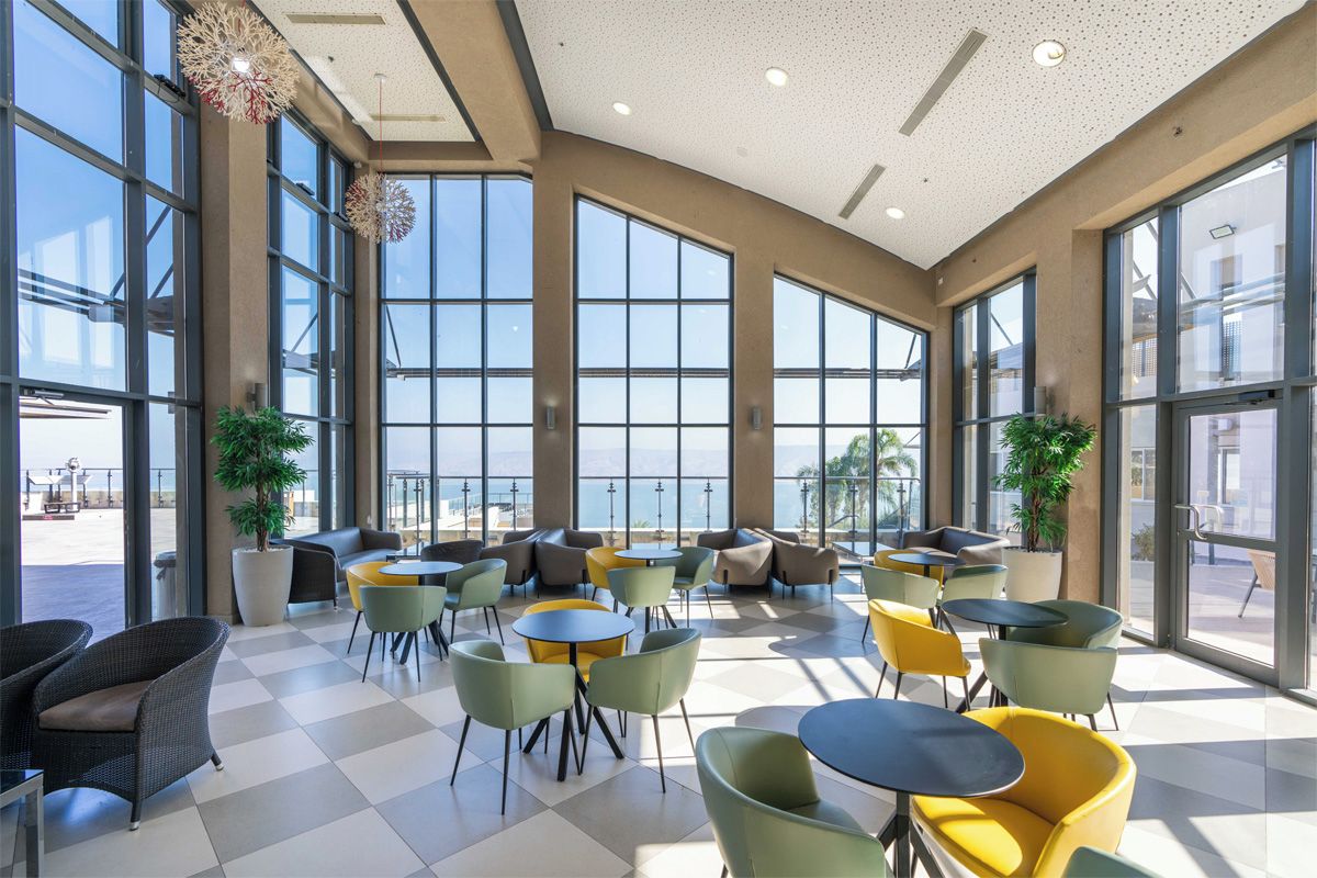 A spacious indoor seating area with large windows, a checkered floor, and various seating options.