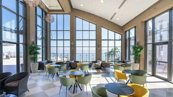 A spacious indoor seating area with large windows, a checkered floor, and various seating options.