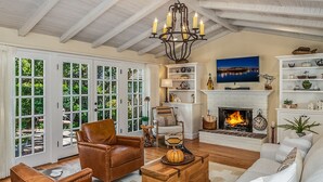 A spacious living room with a fireplace, leather furniture, and a view through large glass doors.