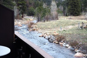 Un río serpentea por un paisaje natural, con una terraza de madera y una mesa en primer plano.