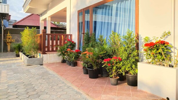 Un edificio residencial con un patio empedrado, plantas en macetas y una cerca de madera.