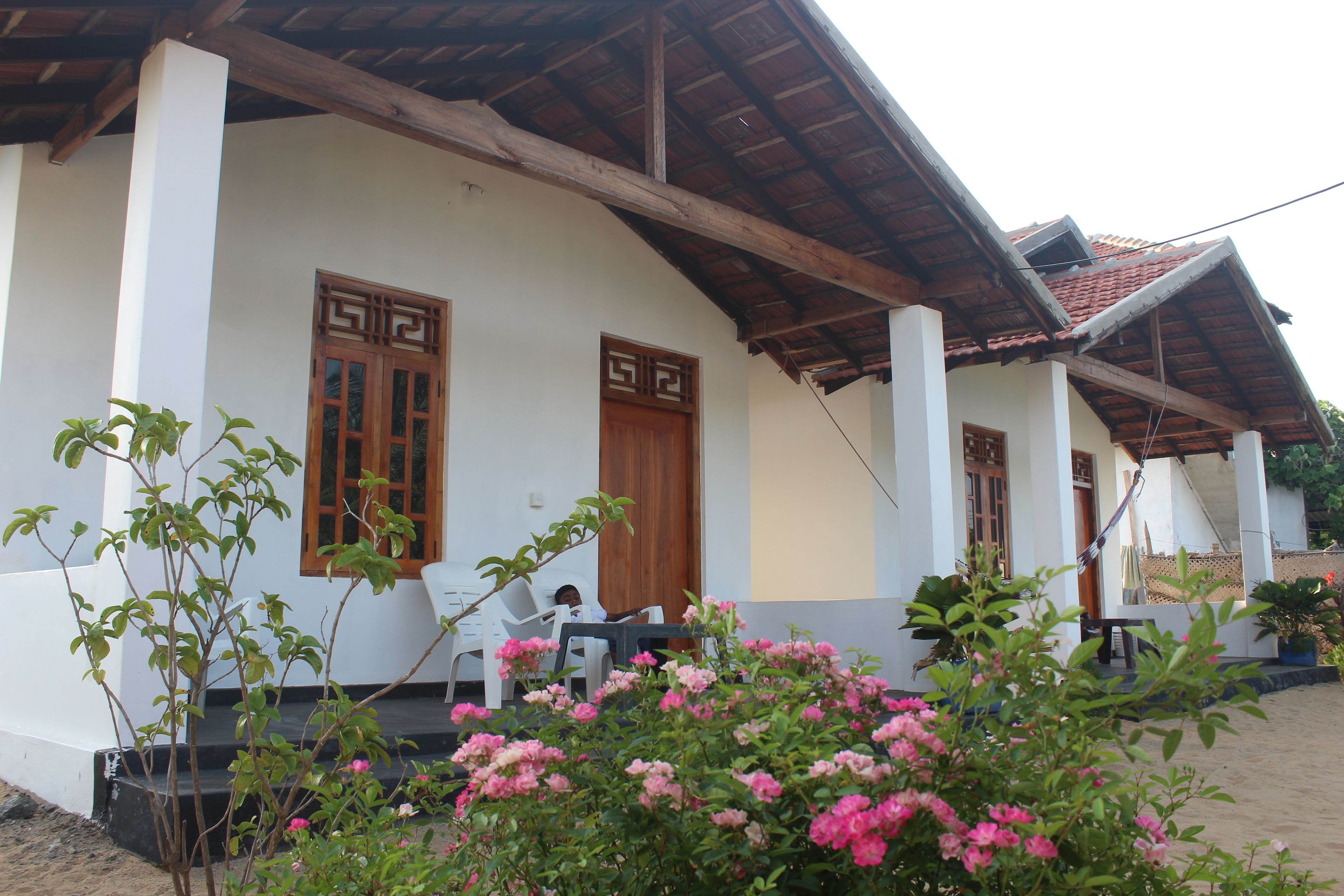 A house with a porch, two wooden doors, and a person sitting at a table.