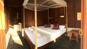 Una habitación de madera con una cama, una mesita de noche y una pequeña mesa.