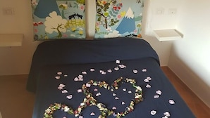 Un dormitorio con una cama, una decoración con forma de corazón hecha de flores y un globo rojo con forma de corazón en la pared.