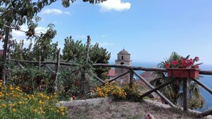 Vista costera con un campanario, una cerca de madera y una maceta con flores.