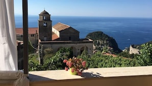 Vista costera con una iglesia y una maceta en un balcón.
