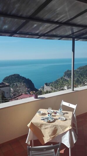 A table set outdoors with a view of the sea. - Casa Falcone B&B (Scala)