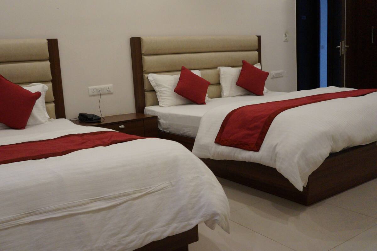 Two beds with headboards, white bedding, and red pillows in a hotel room.
