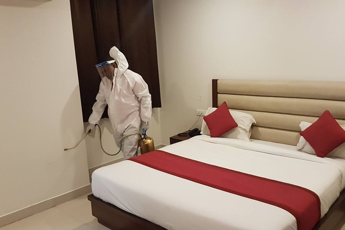A hotel room with a large bed, a bedside table, and a wall-mounted air purifier.