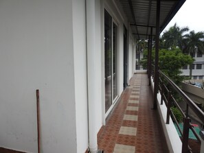 A covered balcony with a tiled floor, large windows, and a metal railing. - Hotel Aakash Residency (Dehradun)