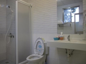 A bathroom with a shower, toilet, sink, and a window with a view of trees. - Sweet Home 101 (Guangfu)