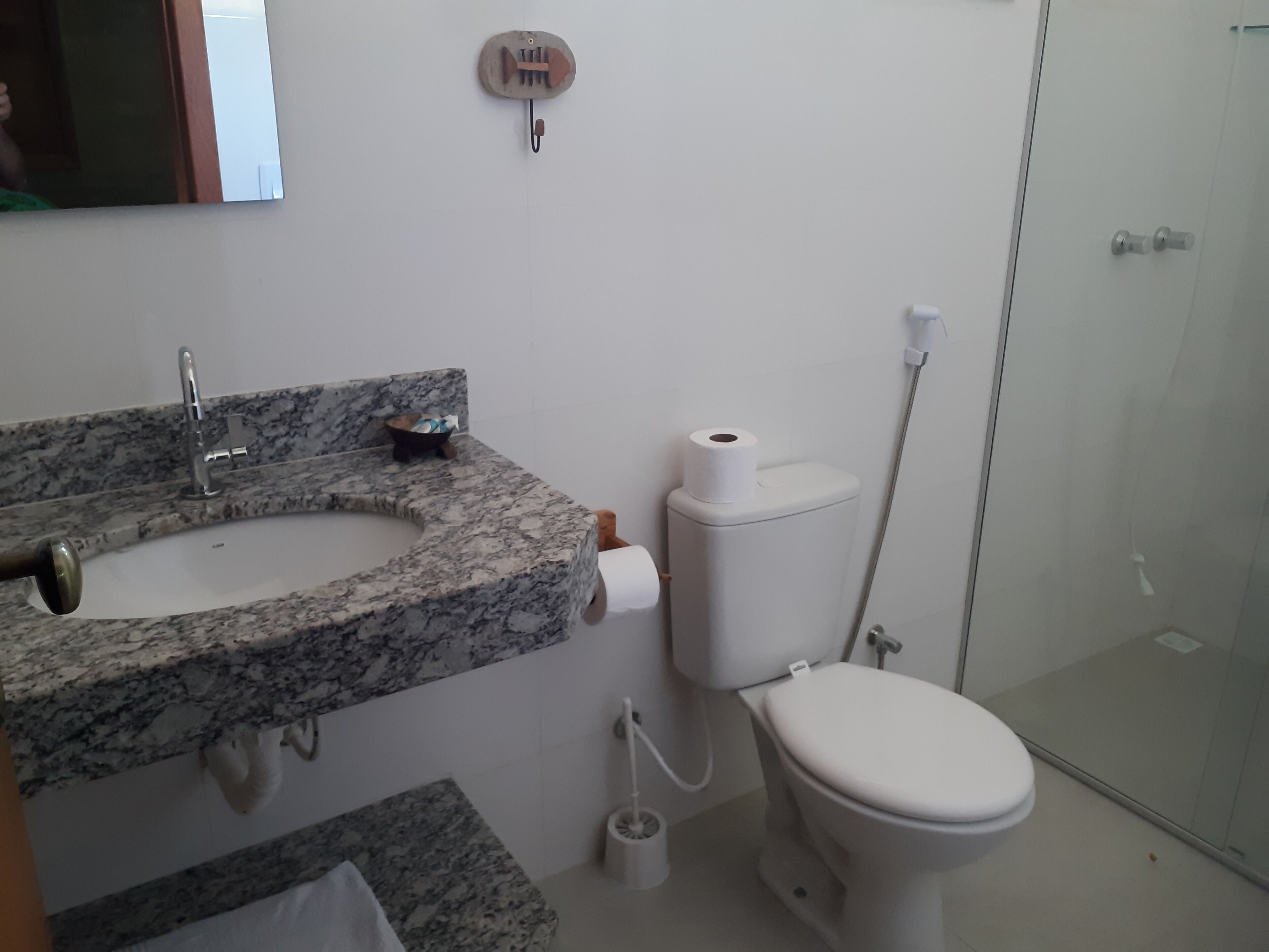 A bathroom with a granite sink, toilet, and shower.