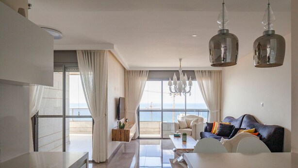 A modern living room with a sofa, a dining table, and a kitchen area. - Luxury Mini Penthouse Sea View Best Loc (Bat Yam)