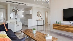 A modern living room with a wooden coffee table, a sofa, and a TV mounted on the wall. - Luxury Mini Penthouse Sea View Best Loc (Bat Yam)