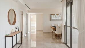 A modern hotel room with a large window, a dining area, and a hallway leading to another room. - Luxury Mini Penthouse Sea View Best Loc (Bat Yam)