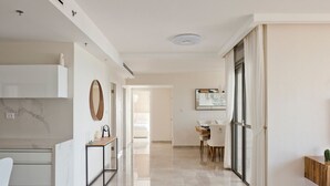 A modern kitchen with a marble countertop, a white chair, and a dining area with a table and chairs. - Luxury Mini Penthouse Sea View Best Loc (Bat Yam)