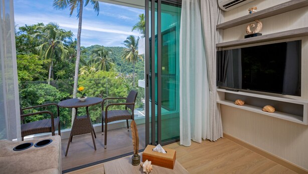 A balcony with wicker furniture, a television, and decorative shells. - Splendid Sea View Resort (Karon)