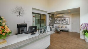 A reception area with a desk, chairs, a computer, and a wall-mounted decorative tree. - Splendid Sea View Resort (Karon)