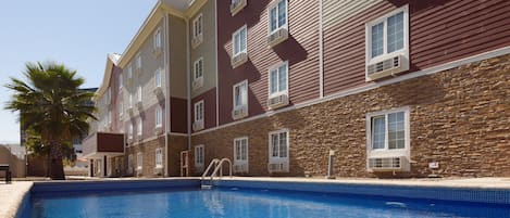 A swimming pool with a stone facade and multiple windows.