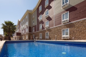 Una piscina con fachada de piedra y múltiples ventanales.