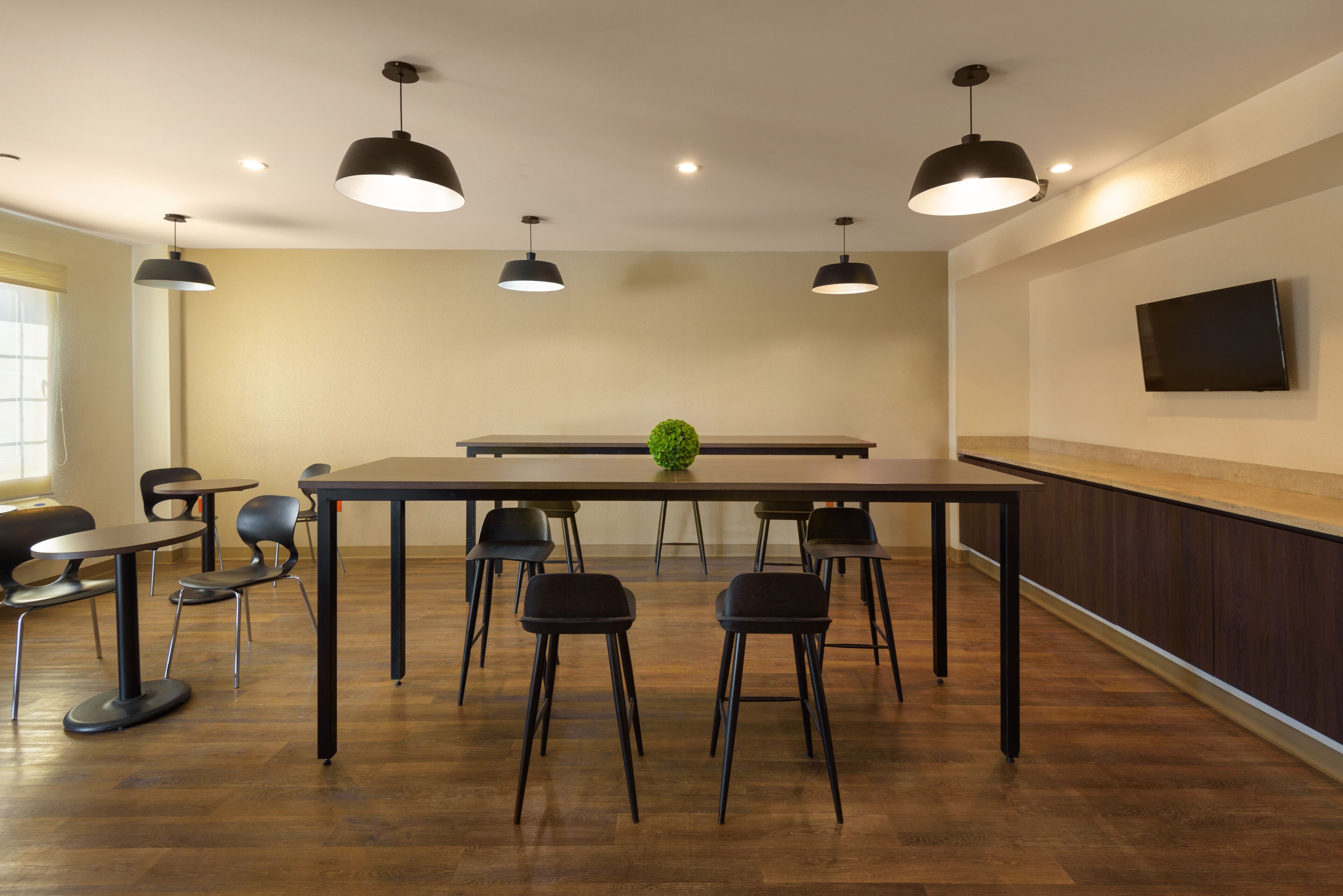 A conference room with a long table, six chairs, and three pendant lights.