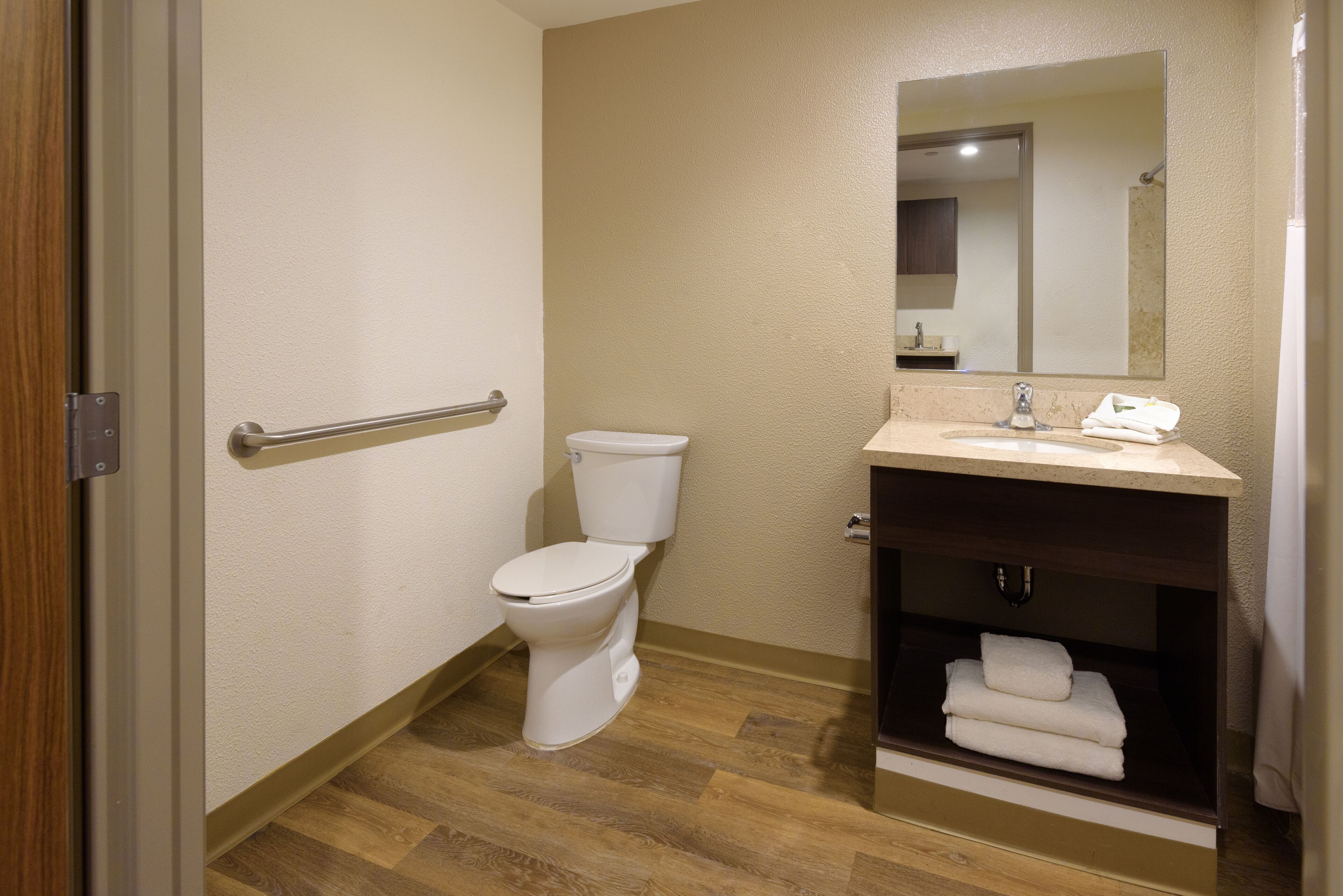 A bathroom with a toilet, sink, and mirror.