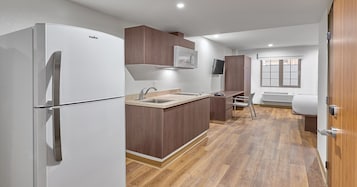 Una cocina compacta con un refrigerador blanco, armarios de madera, un microondas integrado y una ventana con vistas.