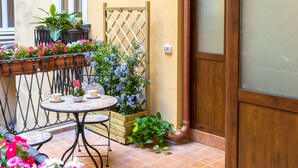 A patio with a table and chairs, potted plants, and a wooden door. - Kings Home In Rome (Rome)