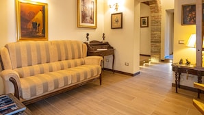 A living room with a sofa, a coffee table with books, a fireplace, and a staircase. - Kings Home In Rome (Rome)
