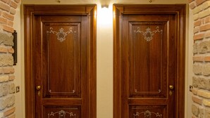 A wooden double door with decorative metalwork, flanked by brick walls and a tiled floor. - Kings Home In Rome (Rome)