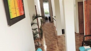 A hallway with a wooden floor, a sofa with blue cushions, and a framed picture on the wall.