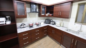 A modern kitchen with dark wooden cabinets, a microwave, a coffee maker, and a sink.