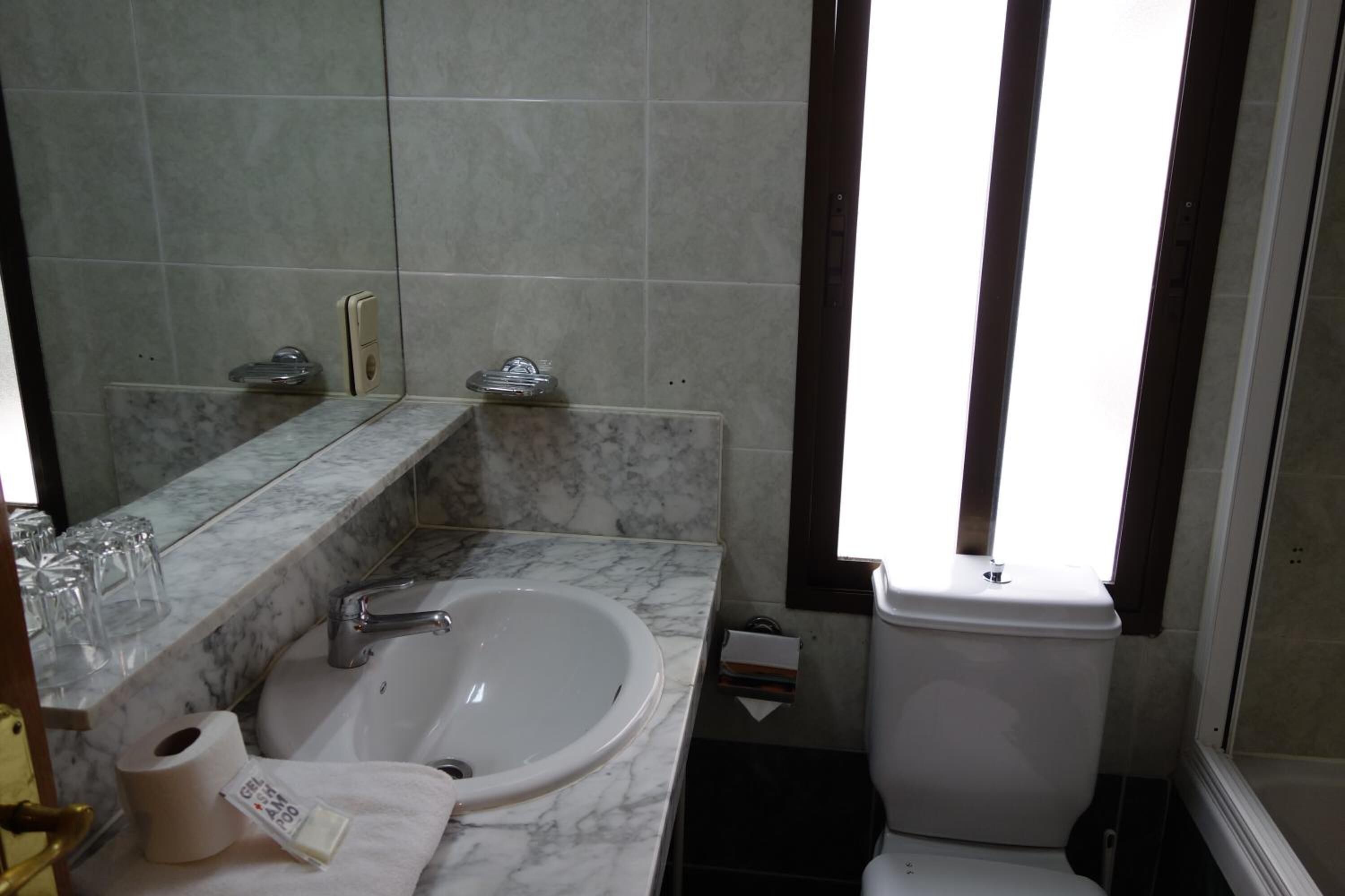 Une salle de bain avec un lavabo en marbre, des toilettes et un miroir.