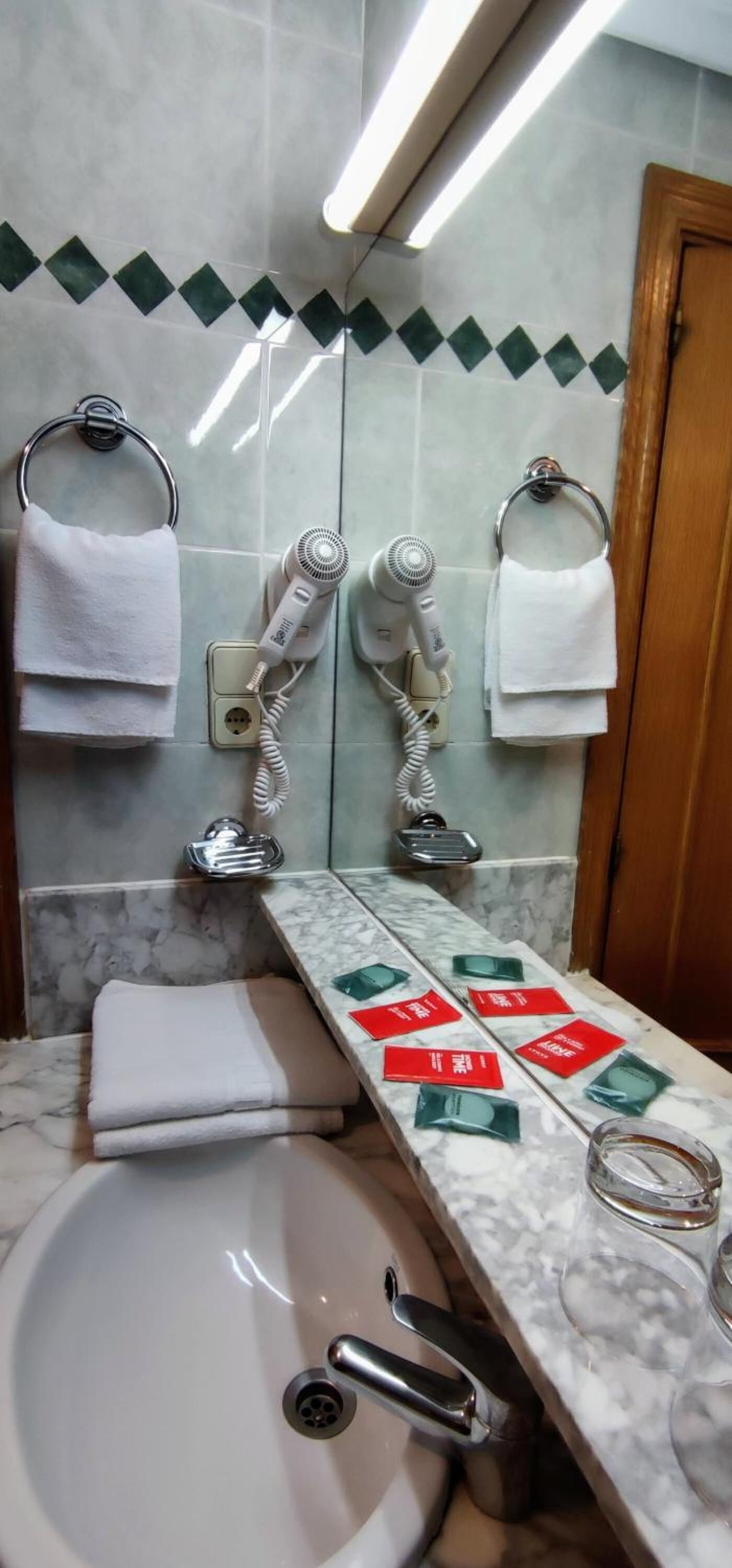 A bathroom with a sink, two hair dryers, and a towel rack.