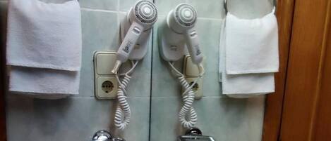 A bathroom with a sink, two hair dryers, and a towel rack.